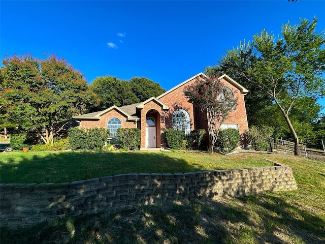 view of front of property featuring an attached garage, brick siding, a front yard, and fence