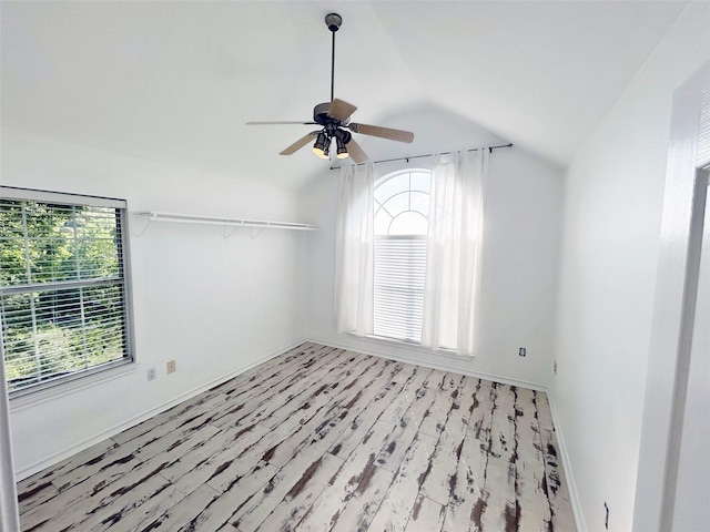 unfurnished room with lofted ceiling, light wood finished floors, a ceiling fan, and baseboards