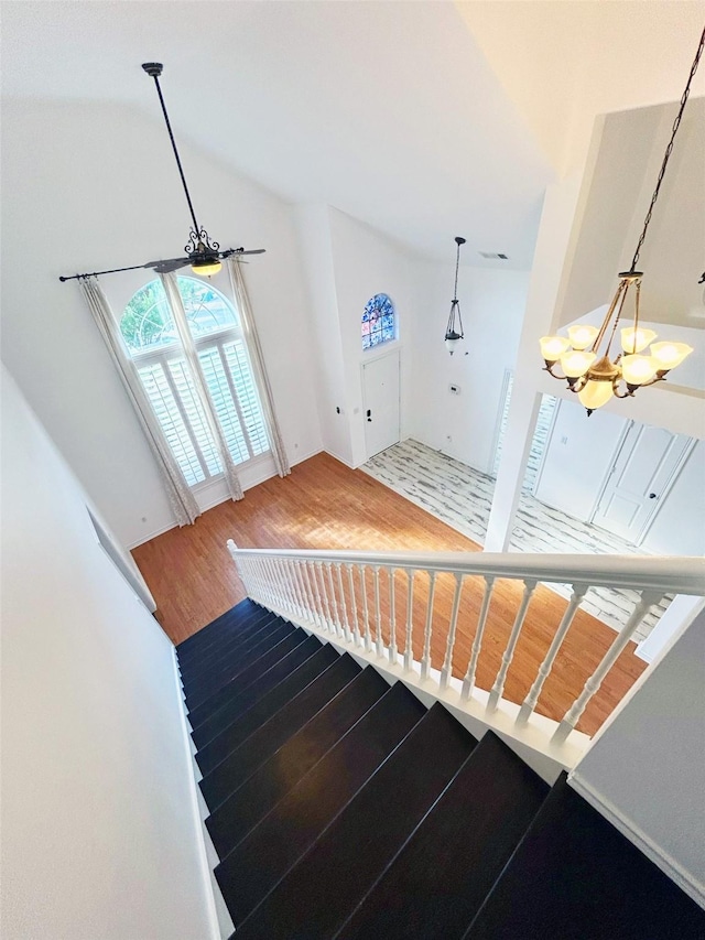 stairs with visible vents, vaulted ceiling, an inviting chandelier, and wood finished floors