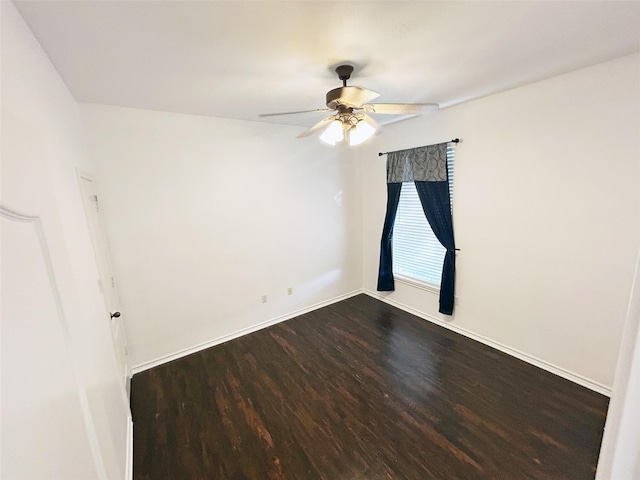 empty room featuring dark wood-style floors, baseboards, and a ceiling fan