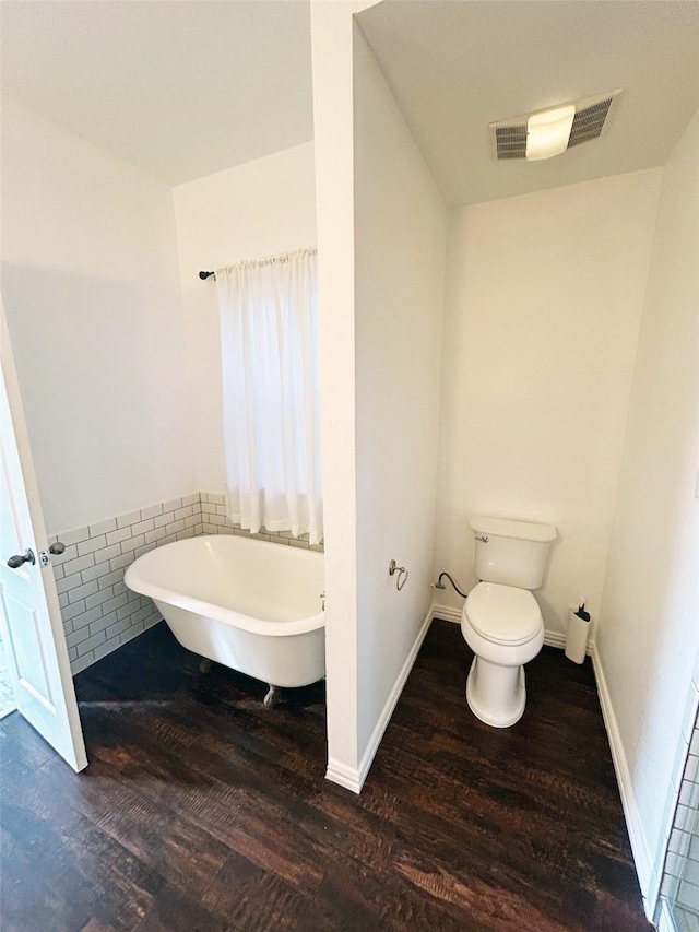 full bath featuring visible vents, a freestanding bath, toilet, wood finished floors, and baseboards