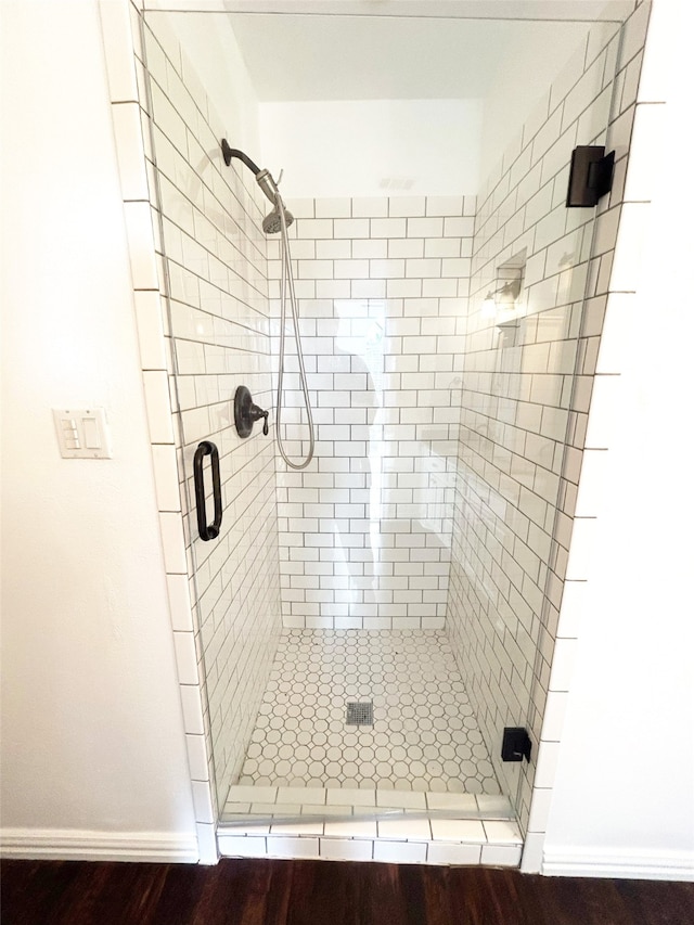 bathroom with a shower with shower door and hardwood / wood-style floors