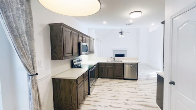 kitchen with a sink, stainless steel appliances, light countertops, and dark brown cabinetry