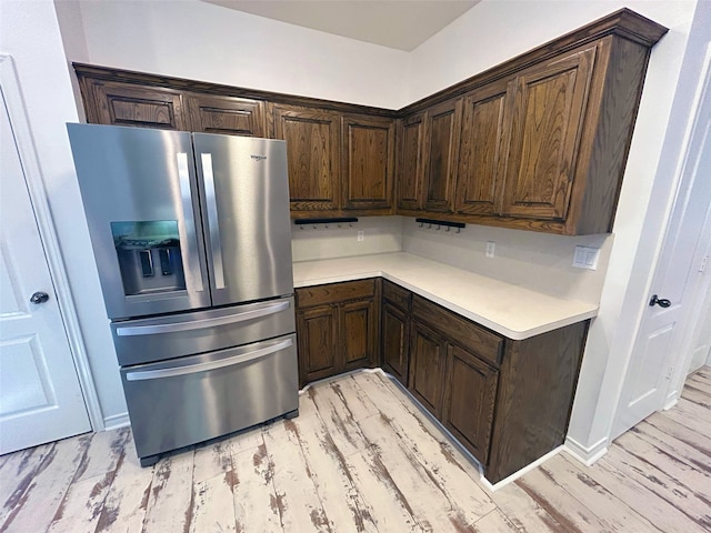 kitchen featuring stainless steel refrigerator with ice dispenser, light hardwood / wood-style floors, and dark brown cabinetry