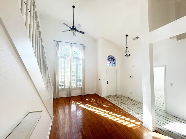 entrance foyer featuring wood-type flooring, a towering ceiling, and ceiling fan