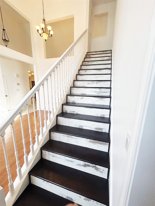 stairs featuring a notable chandelier and hardwood / wood-style flooring