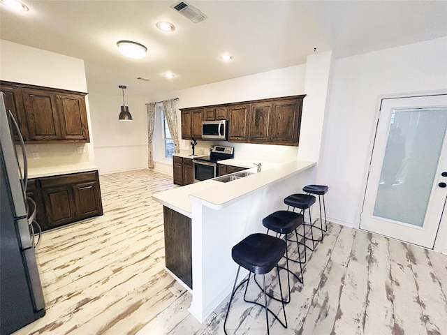 kitchen with light wood-type flooring, sink, kitchen peninsula, a kitchen bar, and stainless steel appliances