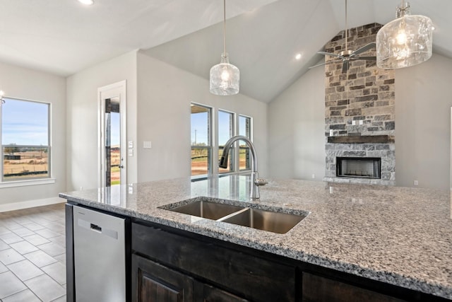 kitchen featuring a fireplace, dishwasher, hanging light fixtures, light stone counters, and sink