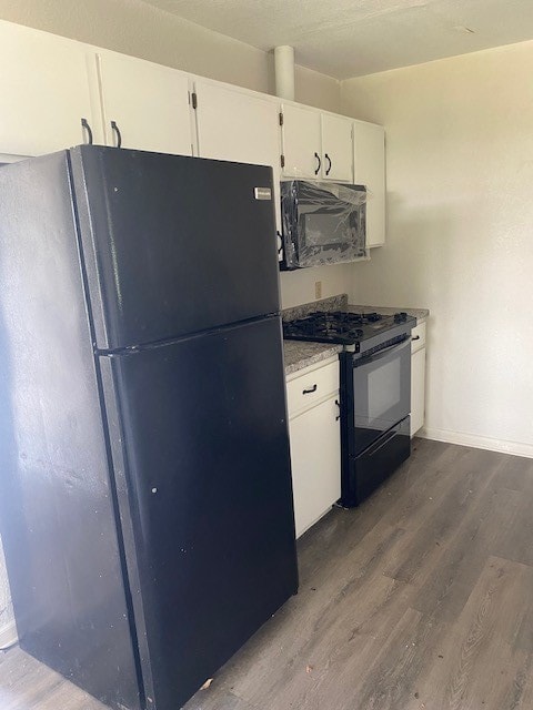 kitchen with black appliances, hardwood / wood-style flooring, and white cabinetry