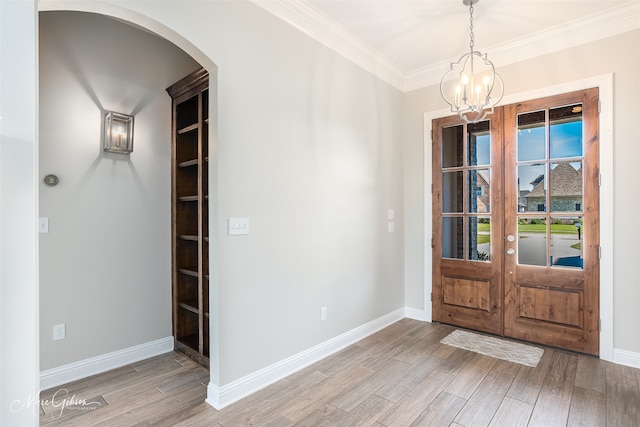 foyer featuring ornamental molding, light hardwood / wood-style flooring, french doors, and a notable chandelier