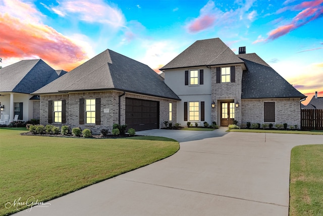 french country home featuring a garage and a lawn