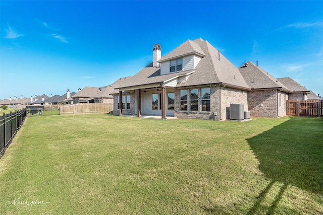 rear view of property with cooling unit, a lawn, and a patio area