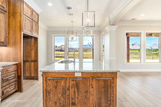 kitchen with an island with sink, light stone countertops, and light hardwood / wood-style flooring