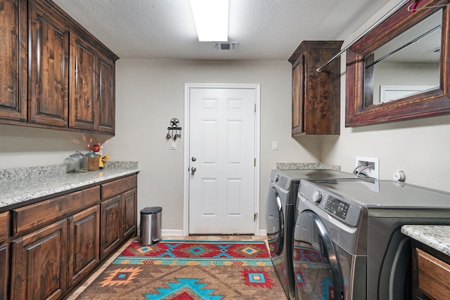 laundry room featuring washer and dryer, cabinets, and a textured ceiling