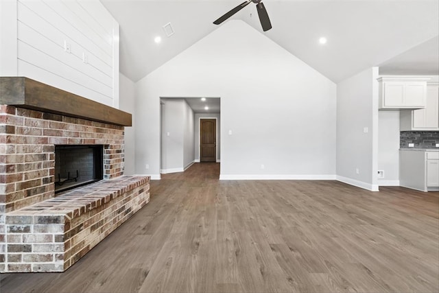 unfurnished living room featuring a brick fireplace, high vaulted ceiling, light hardwood / wood-style flooring, and ceiling fan