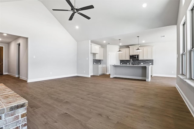 unfurnished living room with ceiling fan, dark hardwood / wood-style flooring, and high vaulted ceiling