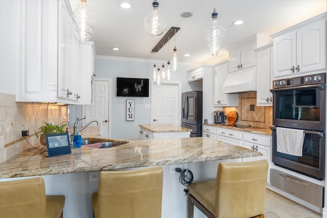 kitchen featuring multiple ovens, stainless steel refrigerator with ice dispenser, light stone countertops, backsplash, and sink