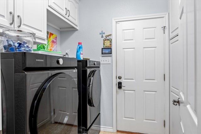 clothes washing area featuring washing machine and dryer, light tile patterned floors, and cabinets