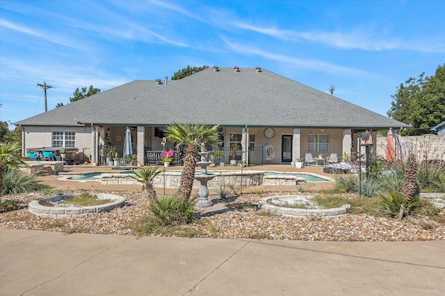 rear view of property with a fenced in pool and a patio area