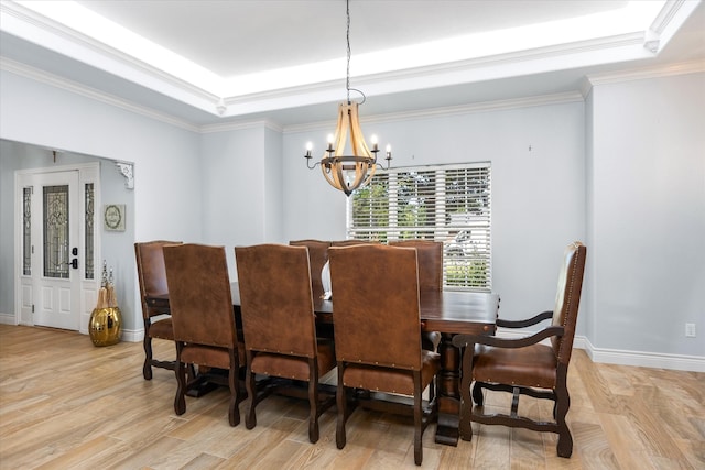 dining room featuring a raised ceiling, crown molding, a chandelier, and light hardwood / wood-style floors