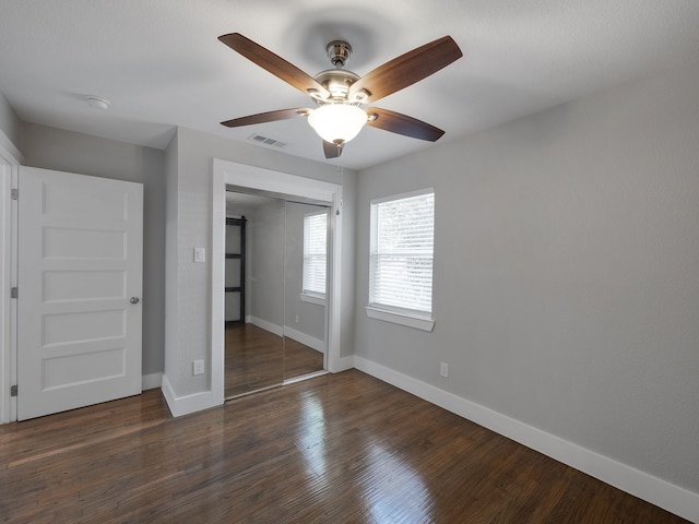 unfurnished bedroom with ceiling fan, dark hardwood / wood-style flooring, and a closet