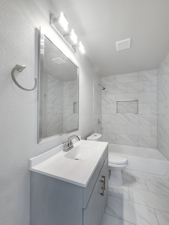 full bathroom with tiled shower / bath combo, vanity, a textured ceiling, and toilet