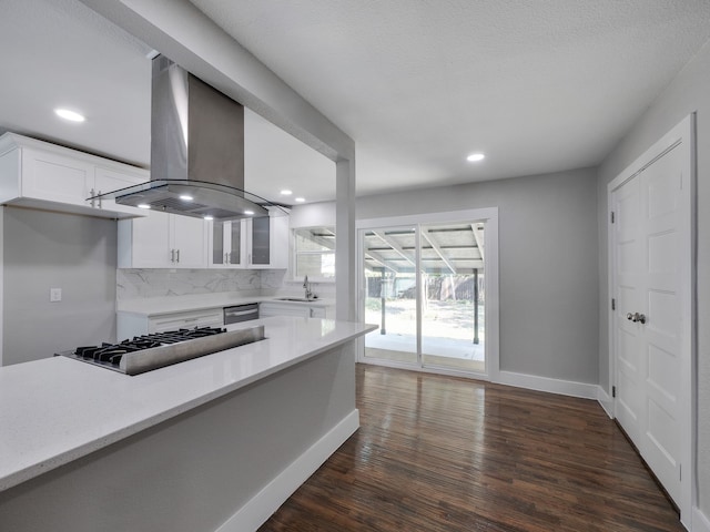 kitchen featuring dark hardwood / wood-style floors, island range hood, stainless steel gas stovetop, white cabinetry, and tasteful backsplash