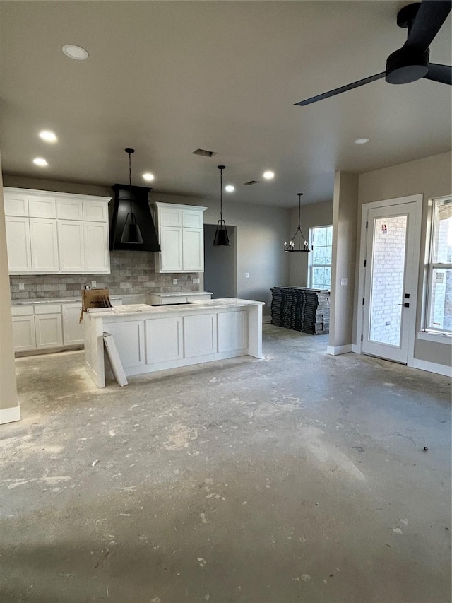 kitchen with pendant lighting, white cabinetry, and custom range hood