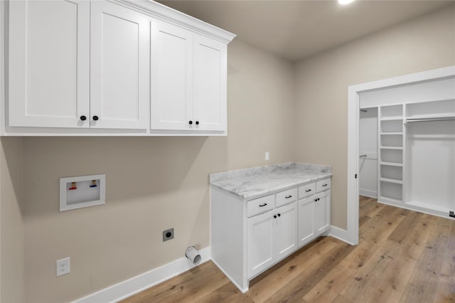 laundry room with electric dryer hookup, hookup for a washing machine, cabinets, and light wood-type flooring