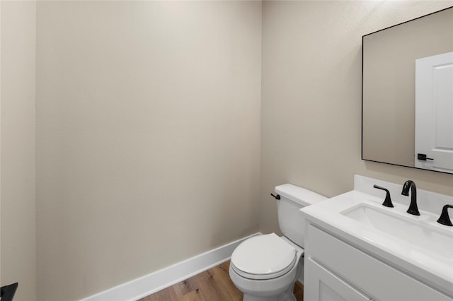 bathroom with wood-type flooring, vanity, and toilet