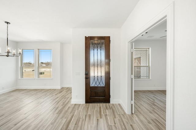 entryway with an inviting chandelier and light hardwood / wood-style flooring