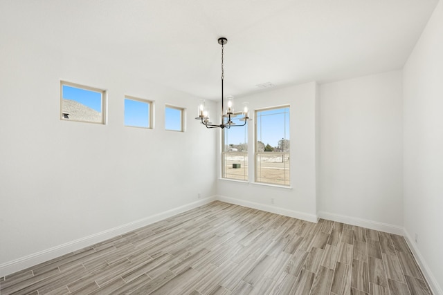 unfurnished dining area with a healthy amount of sunlight, a chandelier, and light hardwood / wood-style floors