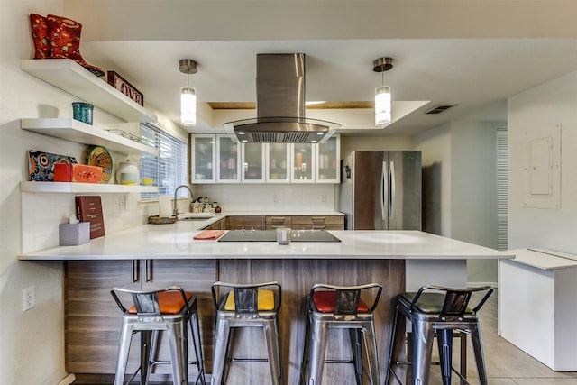 kitchen featuring black electric cooktop, island range hood, a peninsula, a sink, and freestanding refrigerator