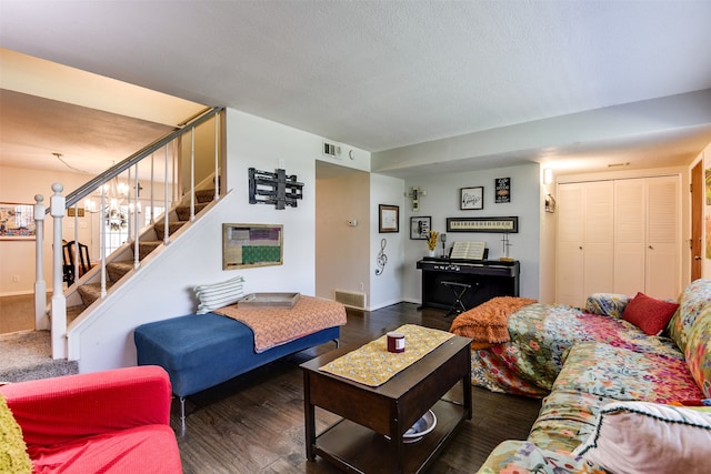 living room with dark wood-style flooring, visible vents, a textured ceiling, and stairs