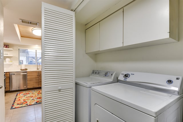 clothes washing area featuring light tile patterned flooring, independent washer and dryer, a sink, and cabinet space