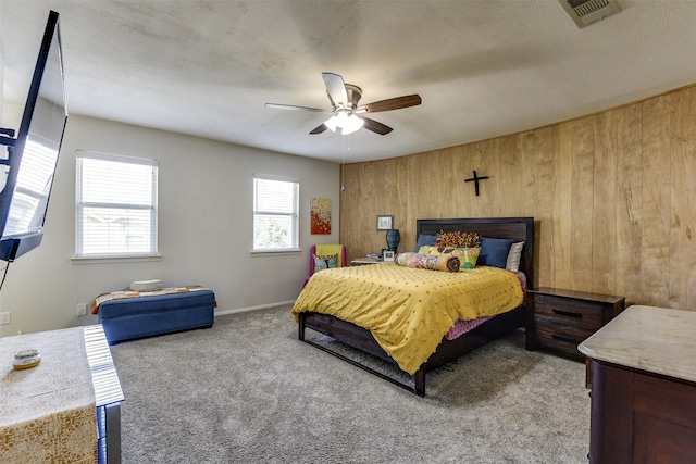 bedroom featuring ceiling fan, carpet floors, multiple windows, and wood walls