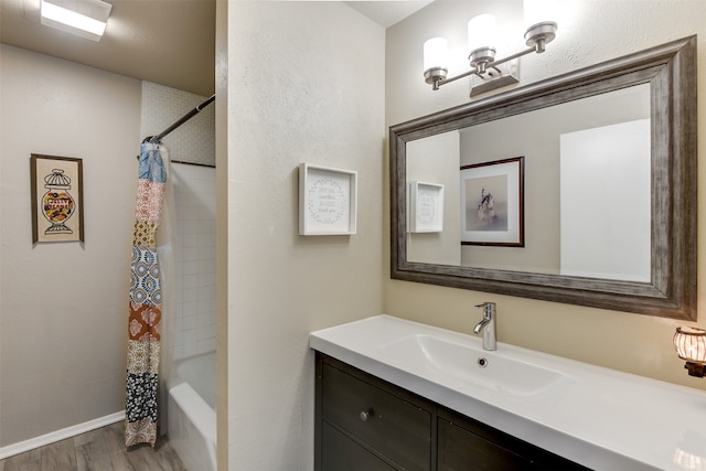 full bath featuring shower / tub combo, baseboards, wood finished floors, and vanity