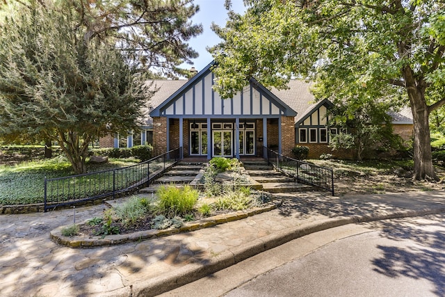 tudor-style house featuring a shingled roof and brick siding