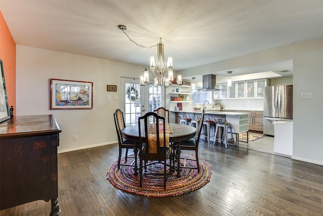 dining area featuring an inviting chandelier, a textured ceiling, baseboards, and dark wood-type flooring