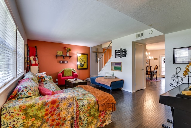 bedroom featuring a textured ceiling, dark hardwood / wood-style flooring, multiple windows, and a notable chandelier