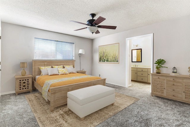 bedroom featuring ceiling fan, sink, a textured ceiling, light colored carpet, and ensuite bath