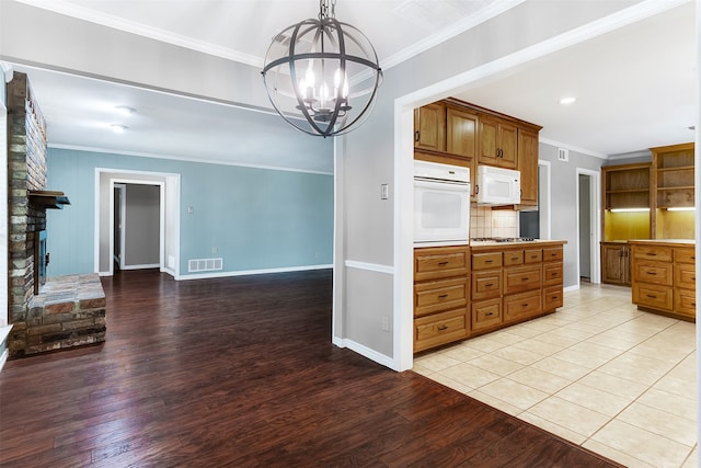 kitchen with light hardwood / wood-style flooring, ornamental molding, white appliances, and a fireplace