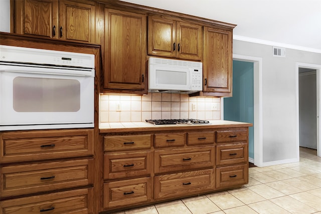 kitchen featuring backsplash, white appliances, ornamental molding, and light tile patterned floors