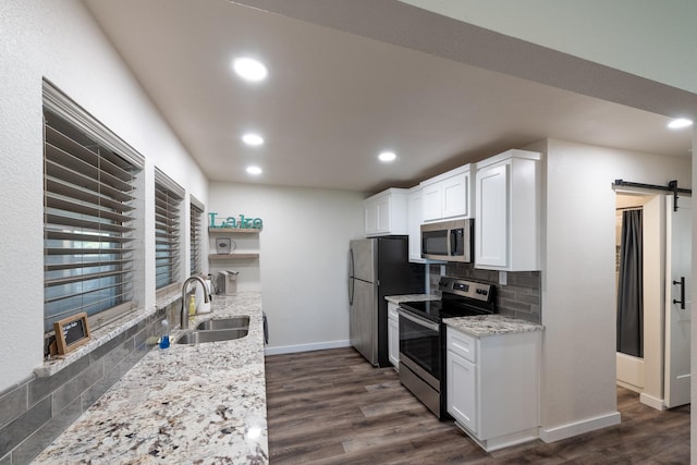 kitchen featuring sink, appliances with stainless steel finishes, a barn door, light stone countertops, and white cabinets