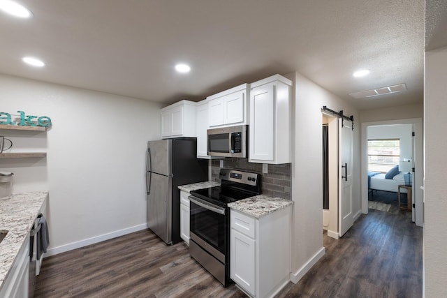 kitchen featuring light stone countertops, a barn door, white cabinets, and appliances with stainless steel finishes