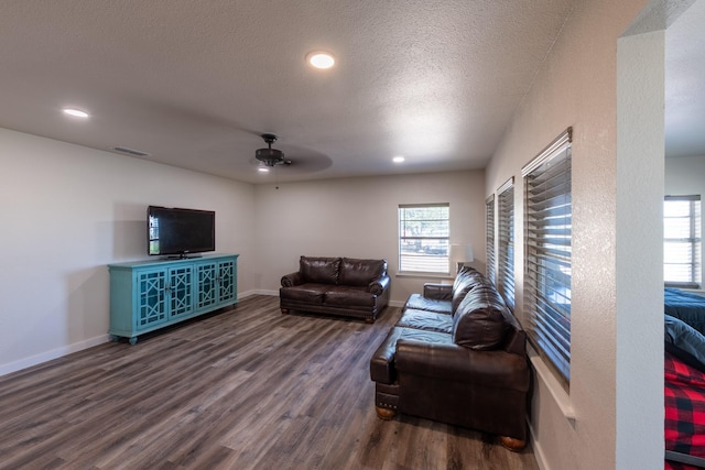 living room featuring ceiling fan, dark hardwood / wood-style flooring, and a textured ceiling