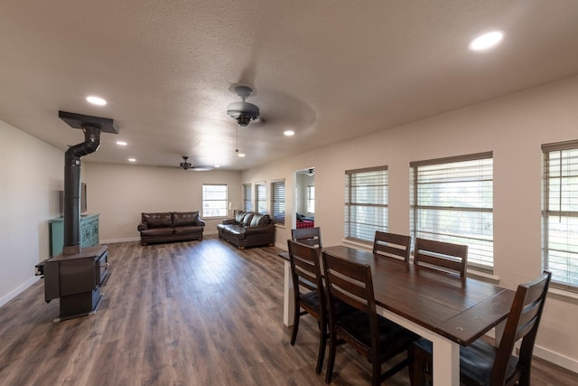 dining room featuring a wood stove, a textured ceiling, dark hardwood / wood-style flooring, and ceiling fan