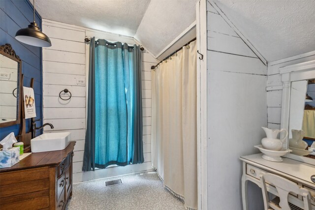 bathroom featuring a textured ceiling, vanity, and lofted ceiling