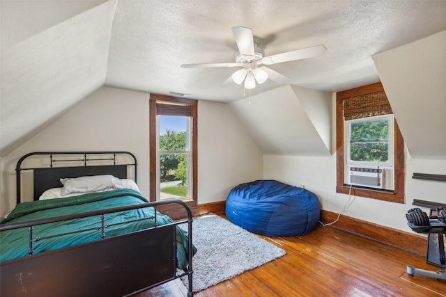 bedroom featuring hardwood / wood-style floors, a textured ceiling, multiple windows, and ceiling fan