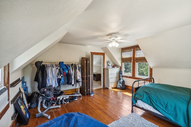 bedroom with ceiling fan, a textured ceiling, vaulted ceiling, and wood-type flooring